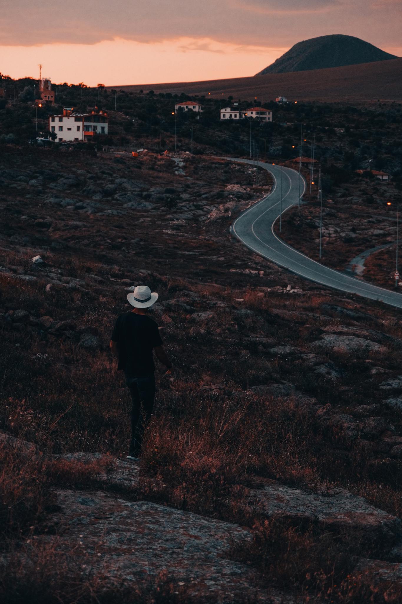 A solitary traveler walks along a winding road at sunset in İncesu, Kayseri, Türkiye.