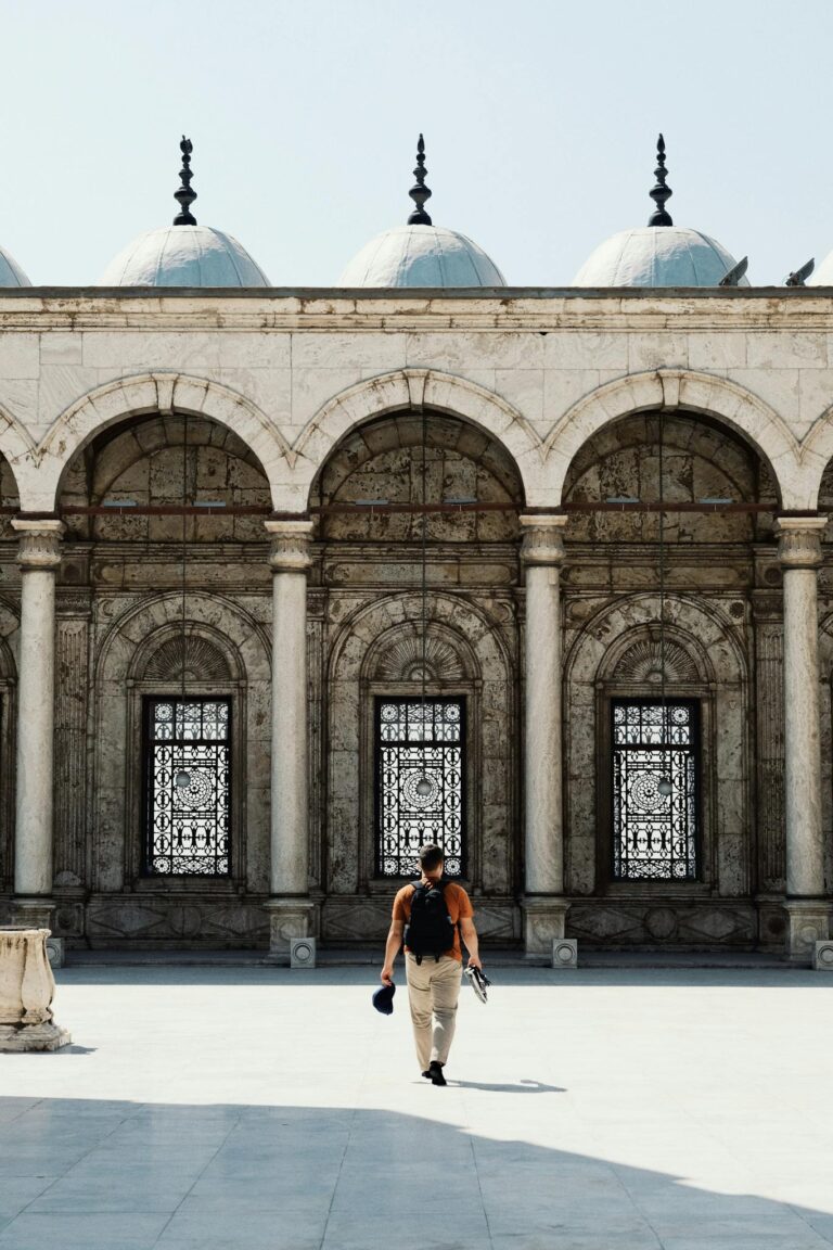 A traveler walking in the courtyard of the Mosque of Muhammad Ali in Cairo, highlighting Islamic architecture.